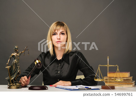 A young fair woman judge works in her office. A young fair woman judge works in her office. 54699761