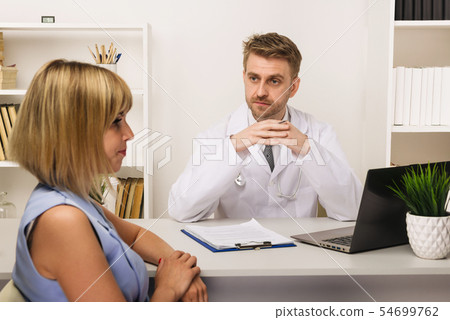 Young woman on a consultation with a male surgeon Young woman on a consultation with a male surgeon 54699762
