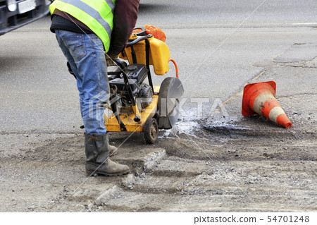 Worker cuts a piece of bad asphalt  54701248
