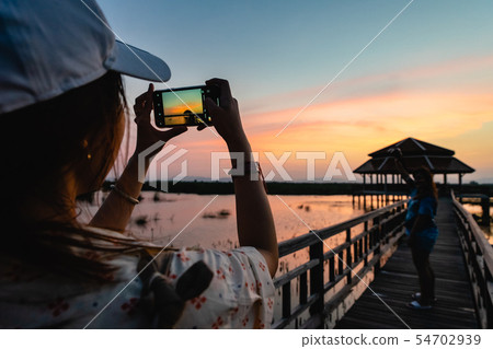 Silhouette of woman taking picture of her friend 54702939