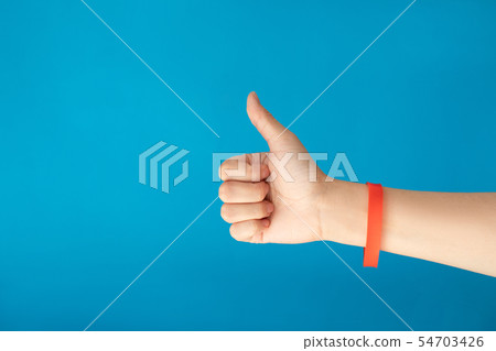 Female hand with empty red bracelet on blue backgr Female hand with empty red bracelet on blue backgr 54703426