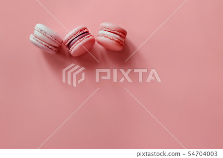 Three macaroons on a coral background. 54704003