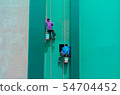 Painters hanging outside of a high building 54704452