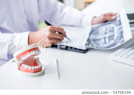 Male doctor or dentist writing report working with 54706199