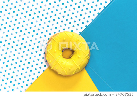 Donut with yellow glaze on yellow blue background. 54707535