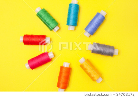Set of multicolored spools of thread on yellow Set of multicolored spools of thread on yellow 54708172