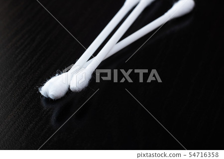 Three cotton buds on a black wooden table 54716358