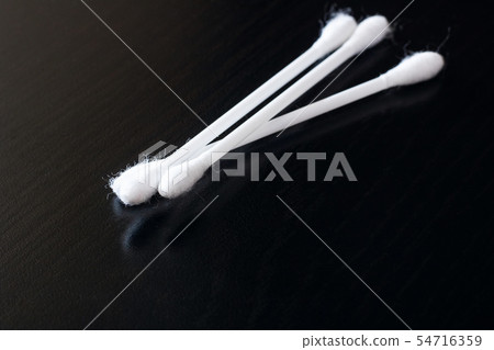 Three cotton buds on a black wooden table Three cotton buds on a black wooden table 54716359