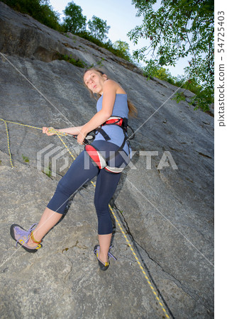 young woman climbing a rock wall young woman climbing a rock wall 54725403