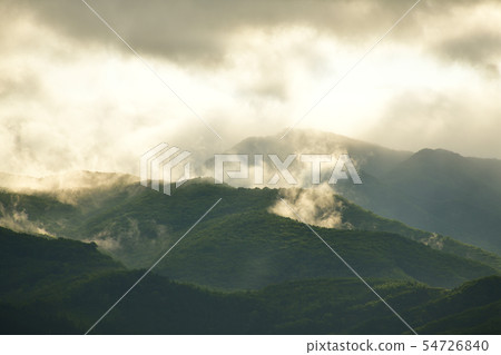 I photographed the scenery where the fog rises from the mountain and the morning sun hits in Hokkaido Nanaecho at dawn 54726840