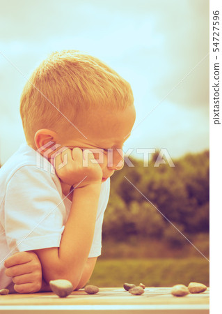 Little boy clever child playing checkers in park Little boy clever child playing checkers in park 54727596