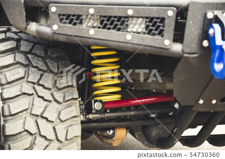 Big off road car coil spring. Yellow shock absorber on the car. Big off road car coil spring. Yellow shock absorber on the car. 54730360