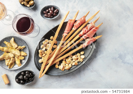 Italian antipasti. Grissini, parma, artichokes, olives, wine, shot from the top with copy space Italian antipasti. Grissini, parma, artichokes, olives, wine, shot from the top with copy space 54731984
