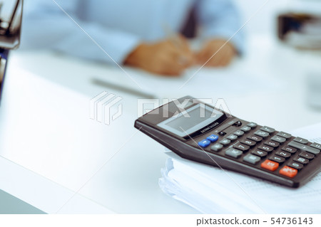 Calculator and binders with papers are waiting to be processed by business woman or bookkeeper back Calculator and binders with papers are waiting to be processed by business woman or bookkeeper back 54736143