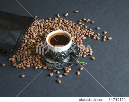 Coffee beans spilled from a package on black table 54739151