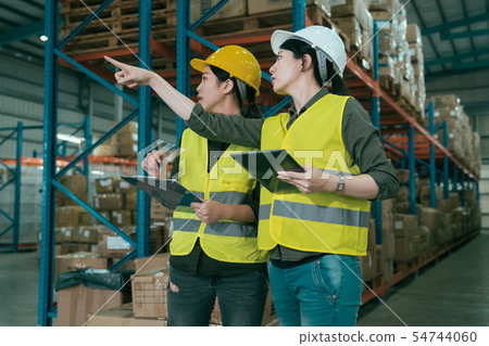 colleagues point finger at shelf in storehouse. 54744060