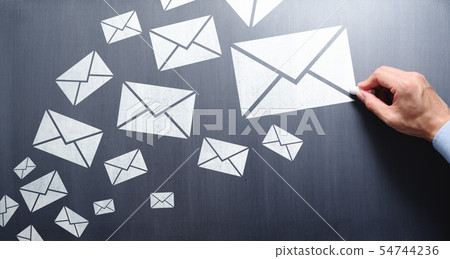 Image to write and send a large amount of mail. Male hand drawing email icon on blackboard. 54744236