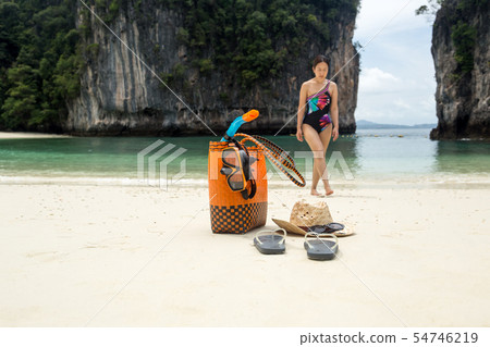 Beach bag and travel accessories with woman in blur background on vacation. 54746219
