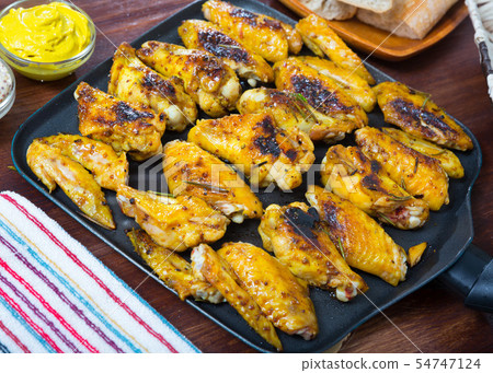 Fried chicken wings on grill pan with sauce 54747124