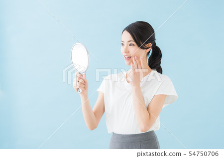 Woman looking at a mirror (blue background) 54750706