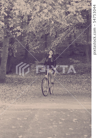 Redhead lady cycling in park. 54753044