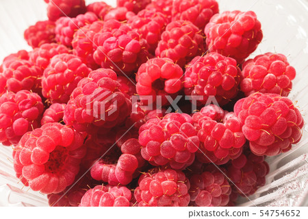 Close-up ripe juicy and delicious raspberry in a plastic transparent dish on a light background 54754652