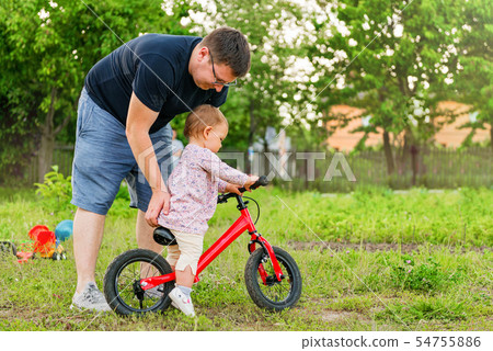 Young father spend time with Cute little one years old toddler girl child and balance bike, father's 54755886