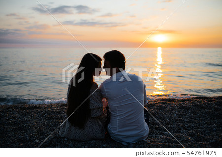Photo of young loving couple at the beach at sunset. Photo of young loving couple at the beach at sunset. 54761975