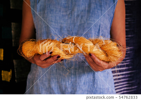 Woman hands holding natural yellow Thai silk fiber 54762833