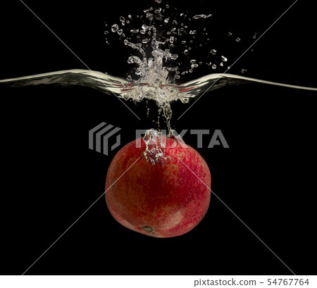 Ripe red pomegranate falling deeply under water with bubbles Ripe red pomegranate falling deeply under water with bubbles 54767764