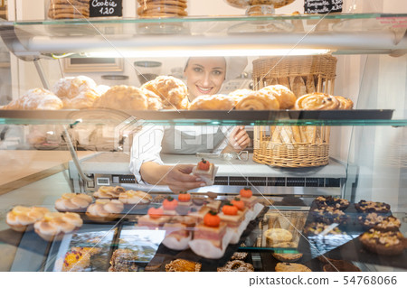 Confectioner shot through glass display in her shop 54768066