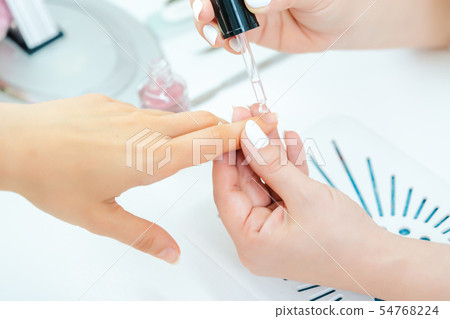 Manicurist pouring oil on finger nails of woman after pedicure Manicurist pouring oil on finger nails of woman after pedicure 54768224