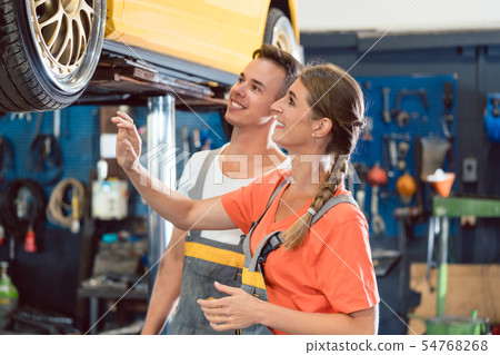 Two dedicated auto mechanics checking the modified wheels of a tuned car 54768268
