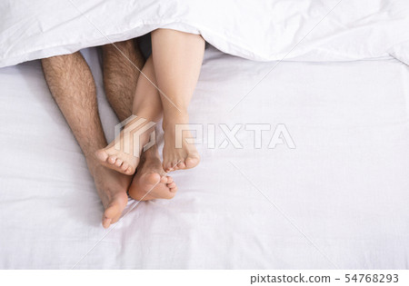 Loving couple legs lying on bed under blanket 54768293