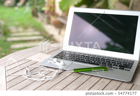 Laptop with ear phones, garden background Laptop with ear phones, garden background 54774177