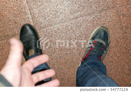 man's hand shows on feet in different shoes man's hand shows on feet in different shoes 54777229