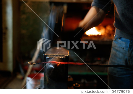 Blacksmith forging red-hot metal with hammer. 54779076