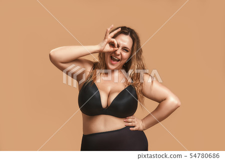 Everything is okay Happy plump woman in black underwear showing ok sign with fingers and winking 54780686