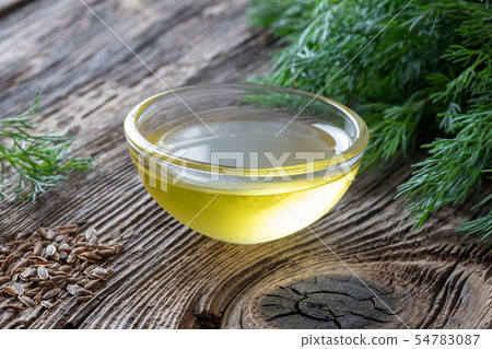 A bowl of dill seed oil with dill seeds and leaves A bowl of dill seed oil with dill seeds and leaves 54783087