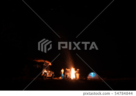 Happy Friends having a rest together around campfire Happy Friends having a rest together around campfire 54784844