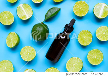 Limes with essential oil on blue background. 54787640