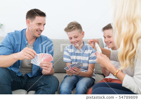 Happy young family playing card game at home. Happy young family playing card game at home. 54789809