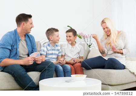 Happy young family playing card game at home. Happy young family playing card game at home. 54789812