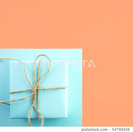Gift of blue color tied with twine on orange. 54790936