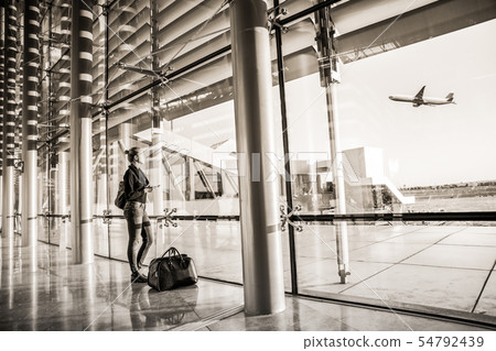 Young woman waiting at airport, looking through the gate window. Young woman waiting at airport, looking through the gate window. 54792439
