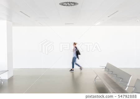 Motion blur of woman walking at contemporary white empty hallway 54792888