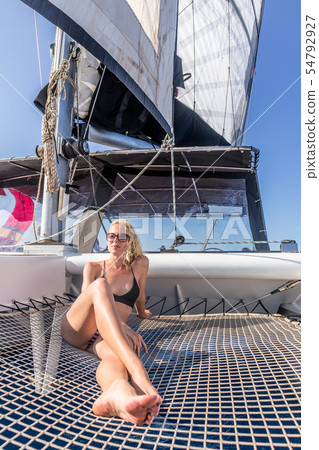 Woman relaxing on a summer sailing cruise, sitting on a luxury catamaran near picture perfect Palau Woman relaxing on a summer sailing cruise, sitting on a luxury catamaran near picture perfect Palau 54792927