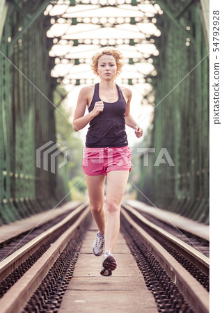 Active sporty woman running on railroad tracks. Active sporty woman running on railroad tracks. 54792928