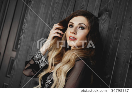 Young pretty woman, wearing transparent black peignoir night gown in dark room Young pretty woman, wearing transparent black peignoir night gown in dark room 54798587