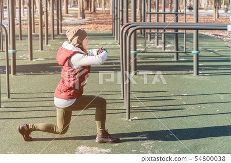 Portrait of a sports girl engaged in a workout in the winter on an outdoor sports field. Lunges and Portrait of a sports girl engaged in a workout in the winter on an outdoor sports field. Lunges and 54800038